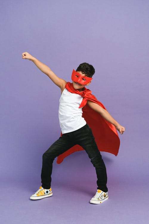 Boy dressed as a superhero with a cape and mask 