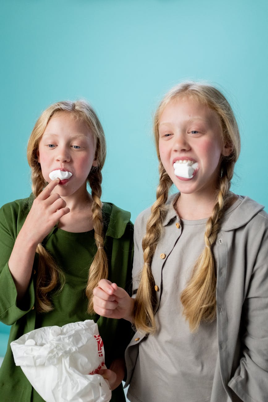 Two girls in braids eating marshmallows 