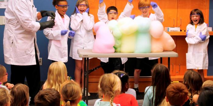 Children dressed as mad scientists playing with colorful foam 