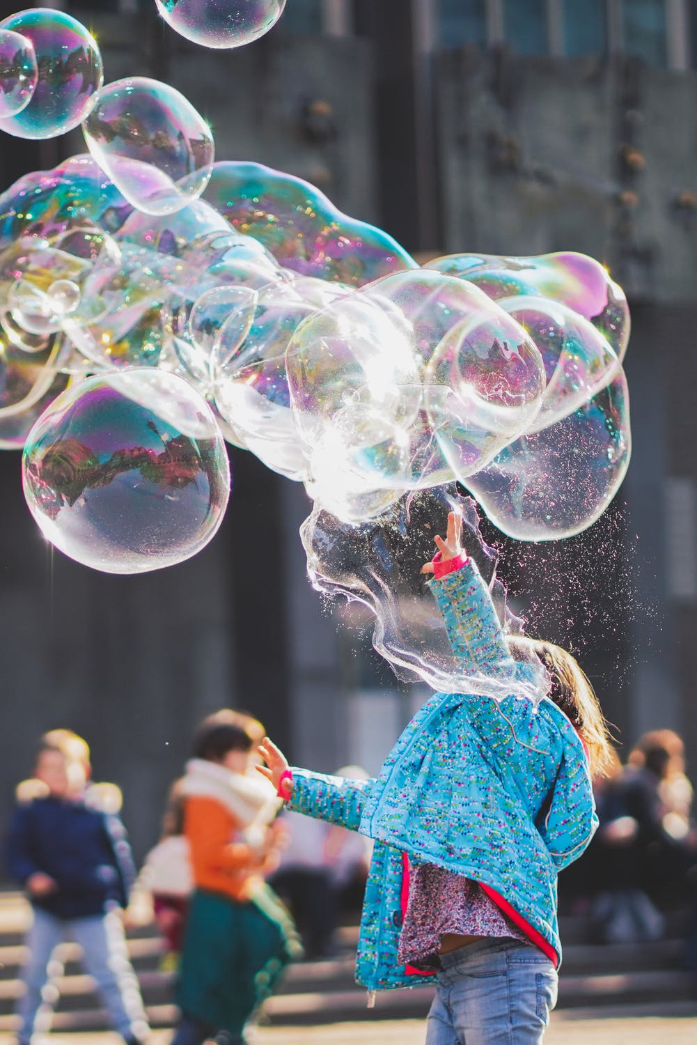 Young child touching and popping large bubbles. 