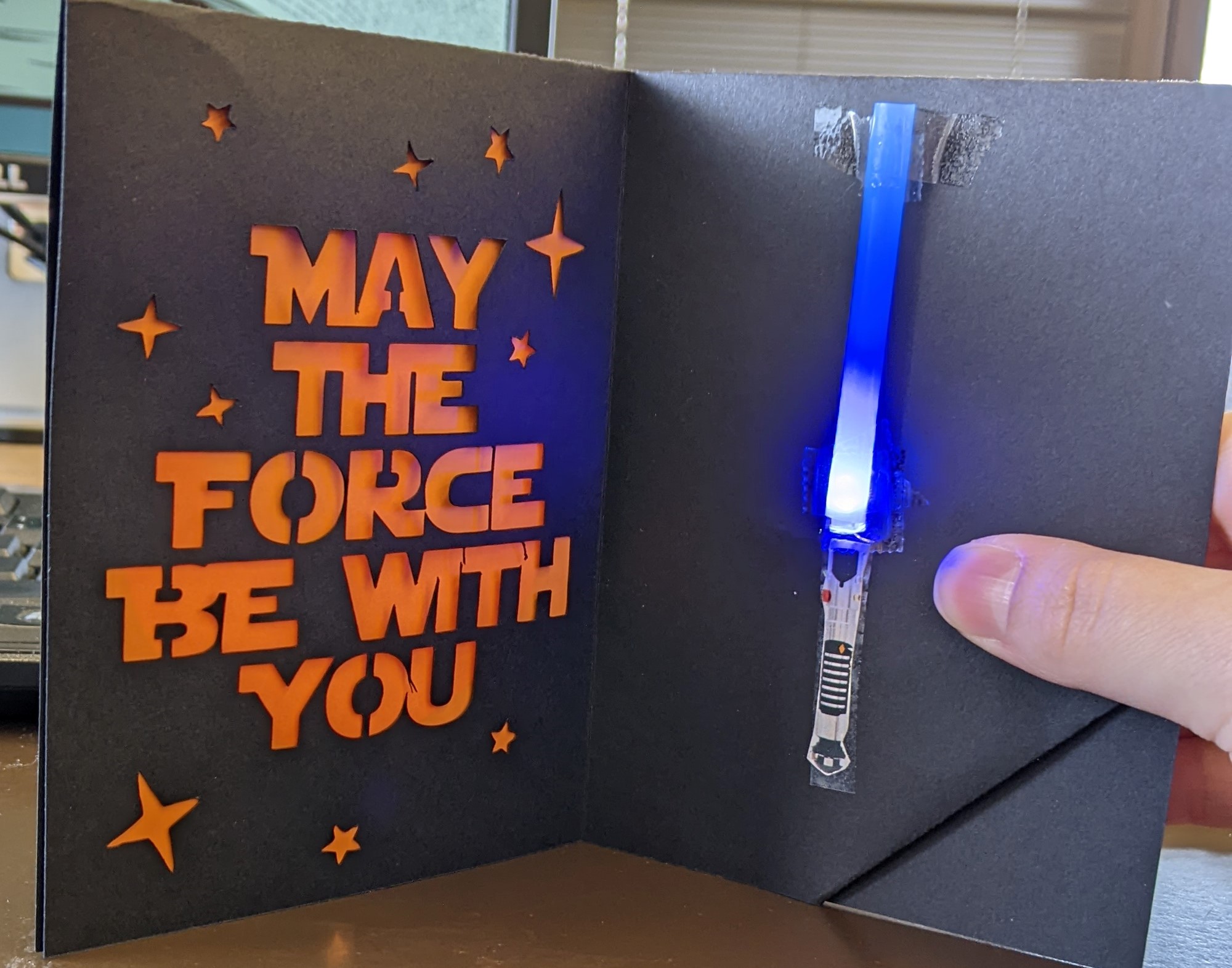 Picture of a handmade light-up card, the card is black with a blue light up component