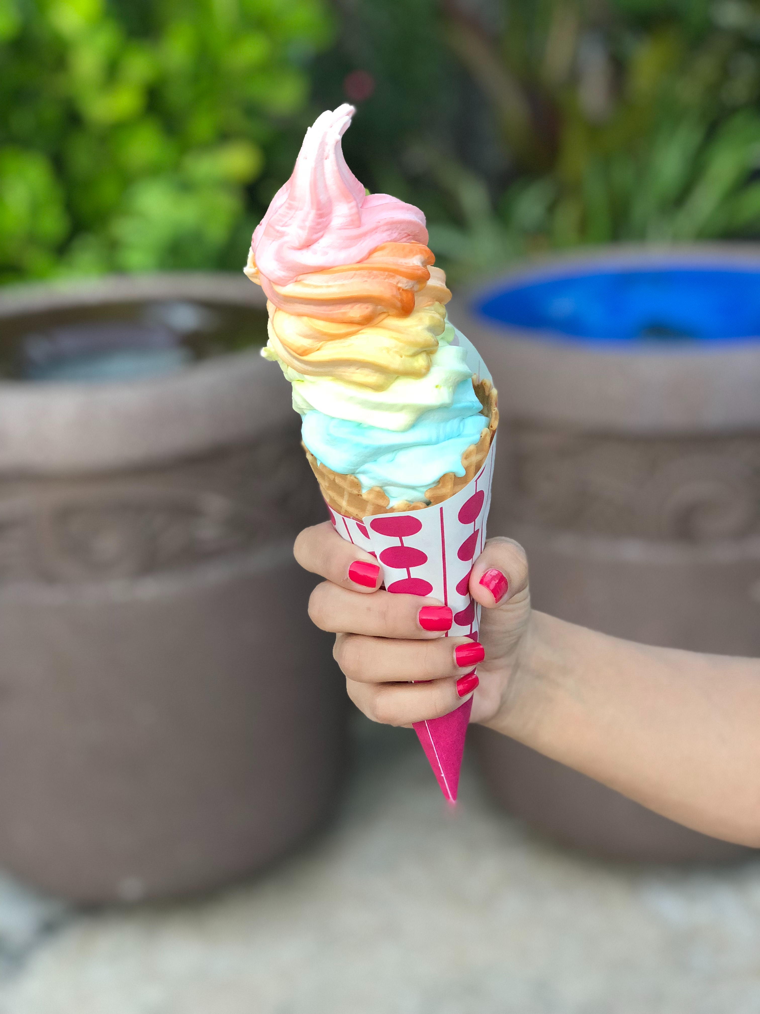 Large, colorful cone of ice cream being held up by a person 