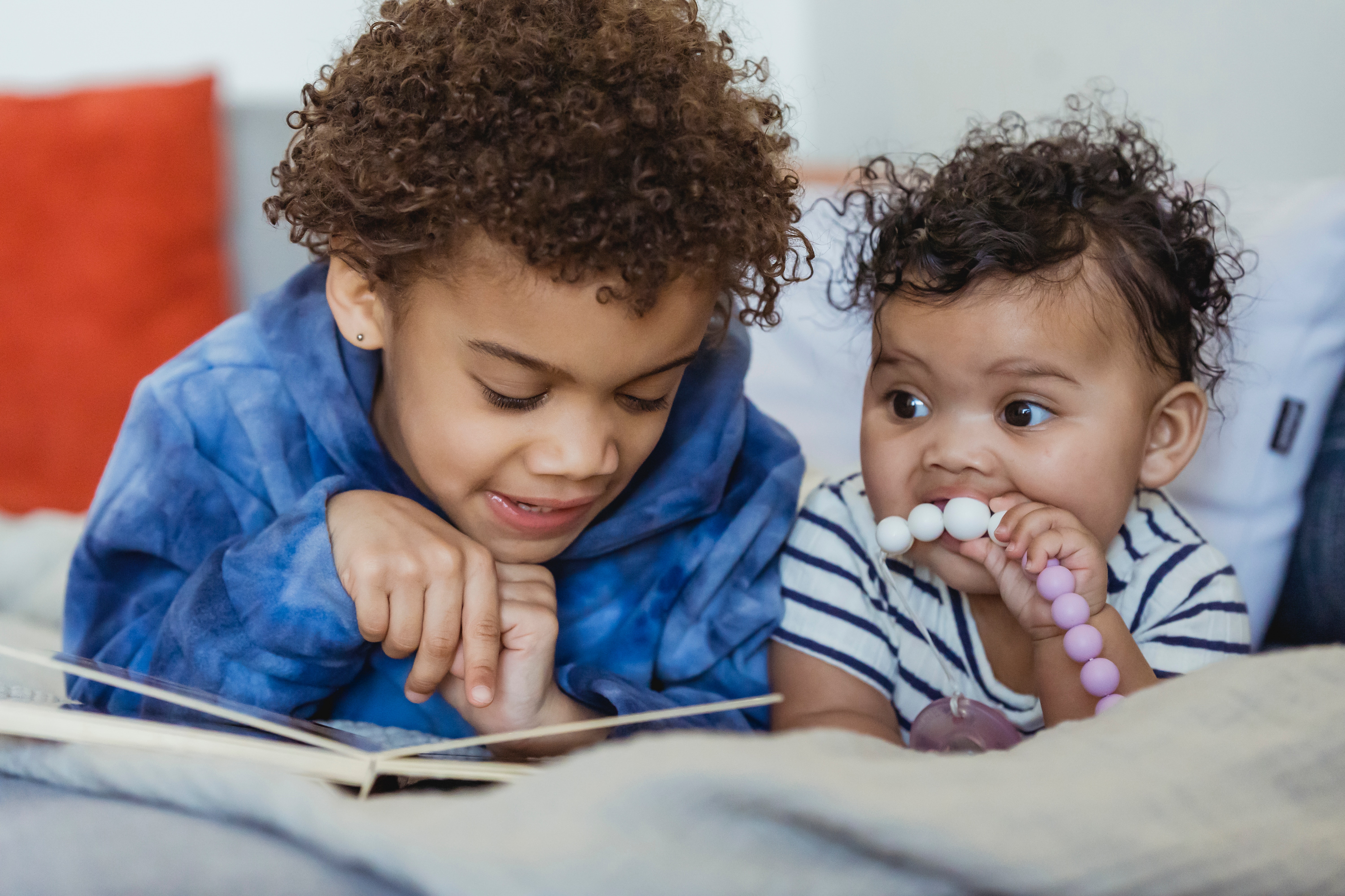 two children laying down, reading 