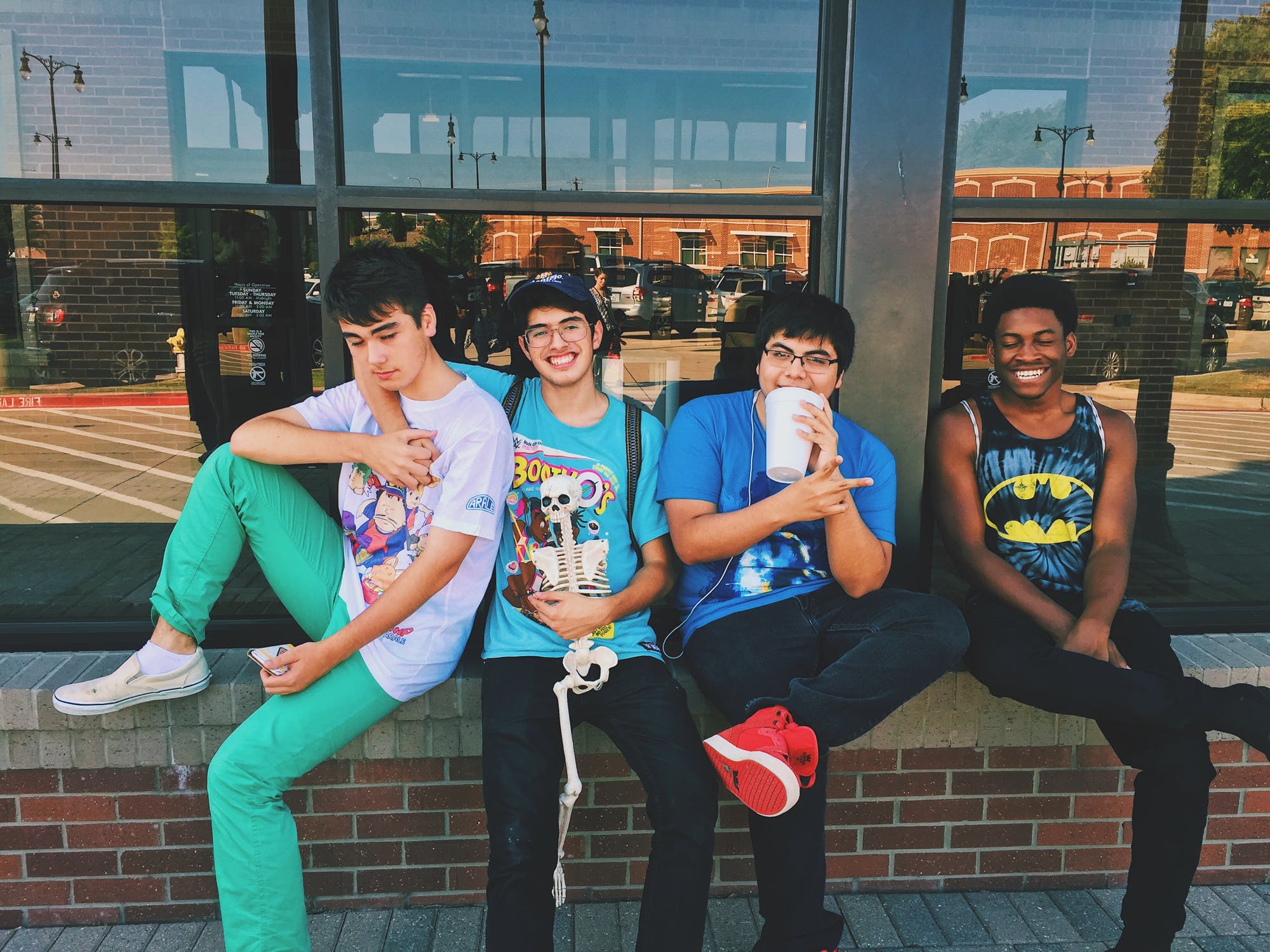 Four teen boys hanging out, outside a building.