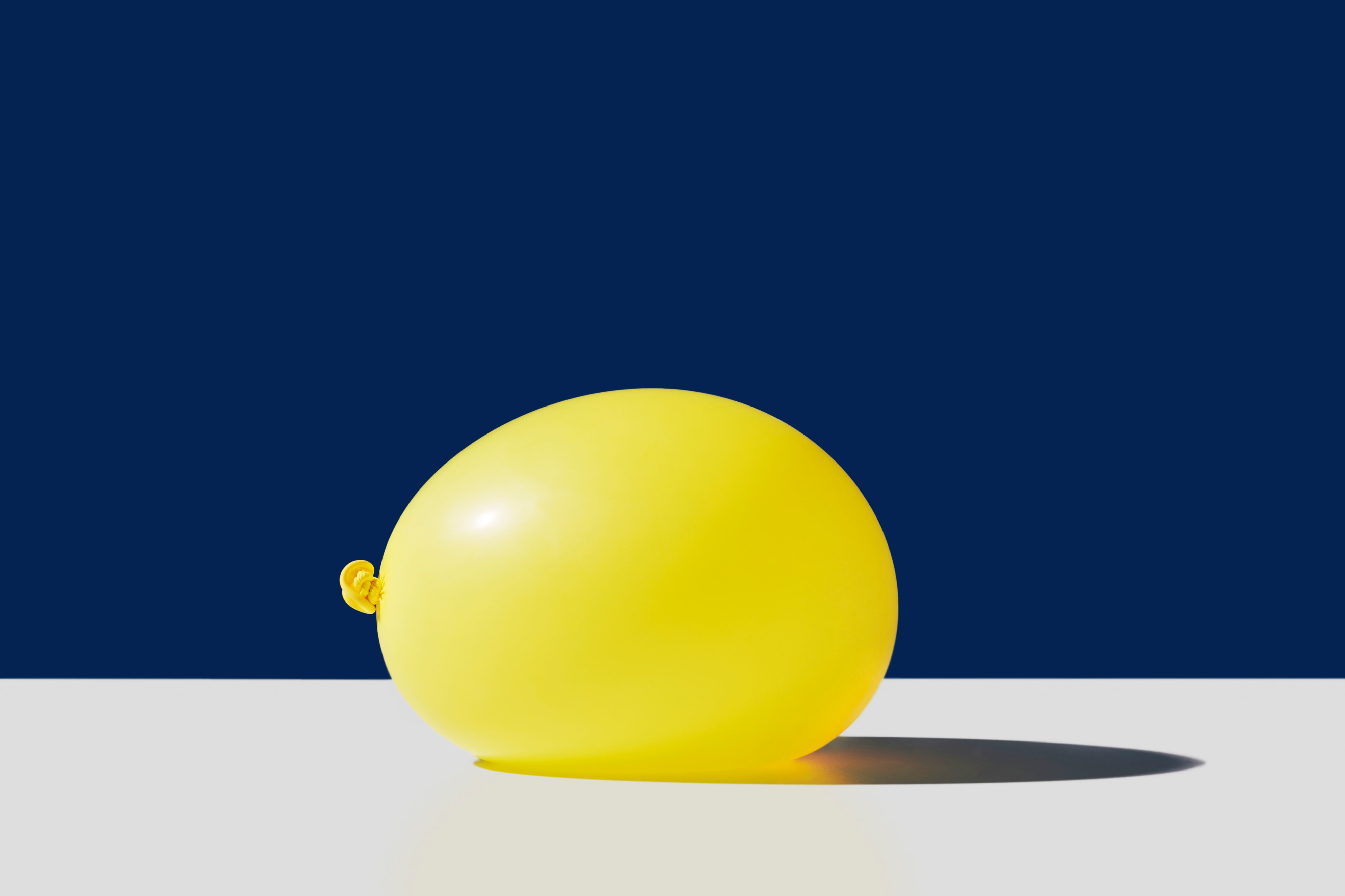 Large yellow balloon on a white surface against a navy background