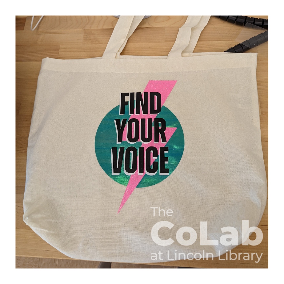 Photo of tote bag with 'Find Your Voice' summer reading logo (a lightning bolt on a circle with the text 'Find Your Voice' on top)