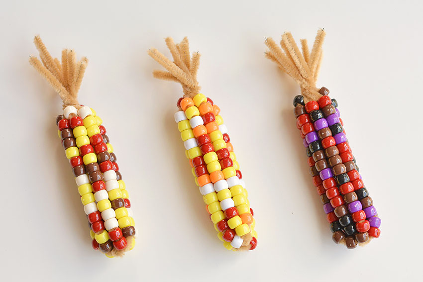 Three small ears of corn, made from multicolored beads and pipe cleaners.