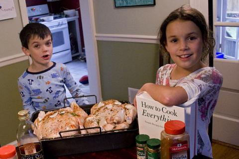 two children cooking chicken