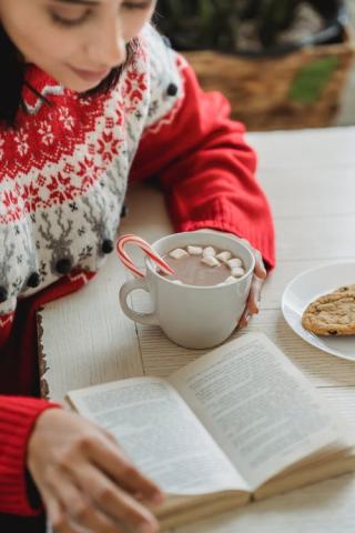 Girl drinking hot chocolate and reading a book 