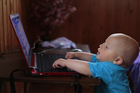 A infant sitting in front of a computer