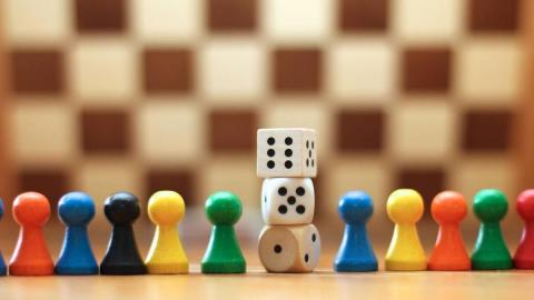 a close up picture of several colorful game pieces. In the middle is a stack of 3 6-sided dice.