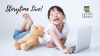 Young child laughing with teddy bear in front of a laptop computer