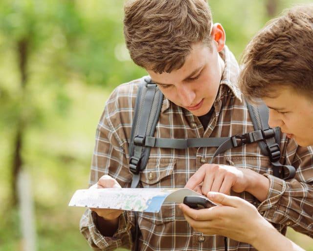 Two teen boys studying a map. 