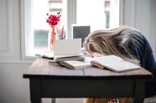 A very tired teen with her head down on the table. 